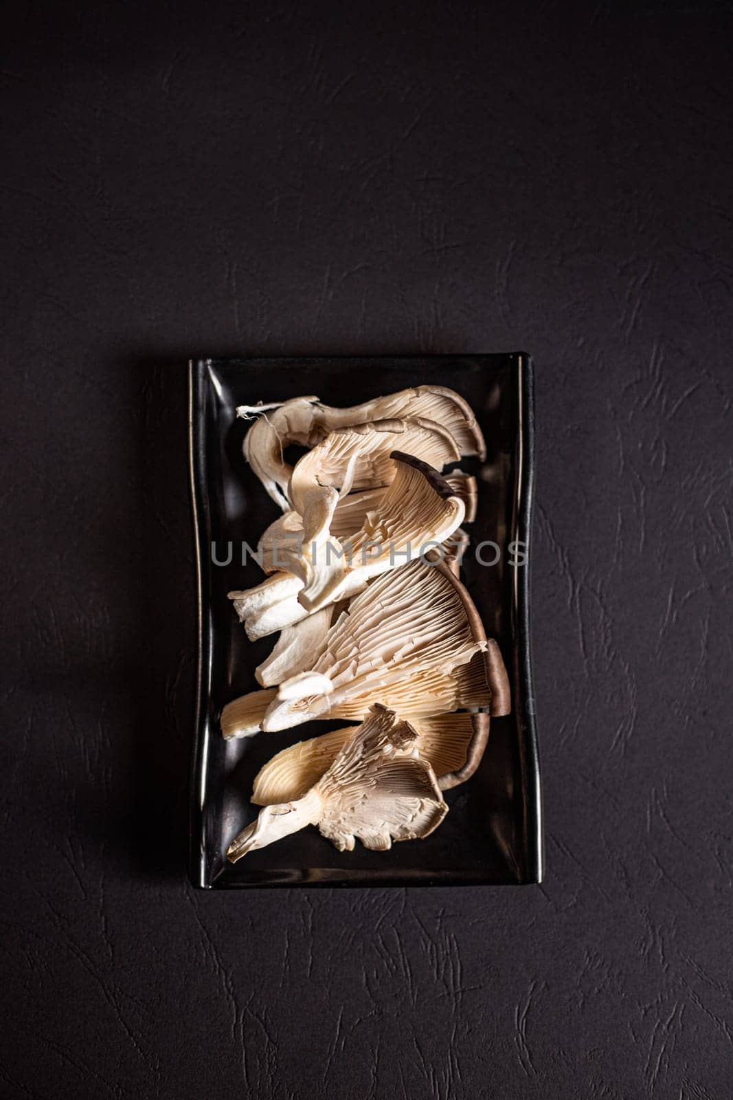 fresh and raw oyster mushrooms on a black plate view from above by tewolf