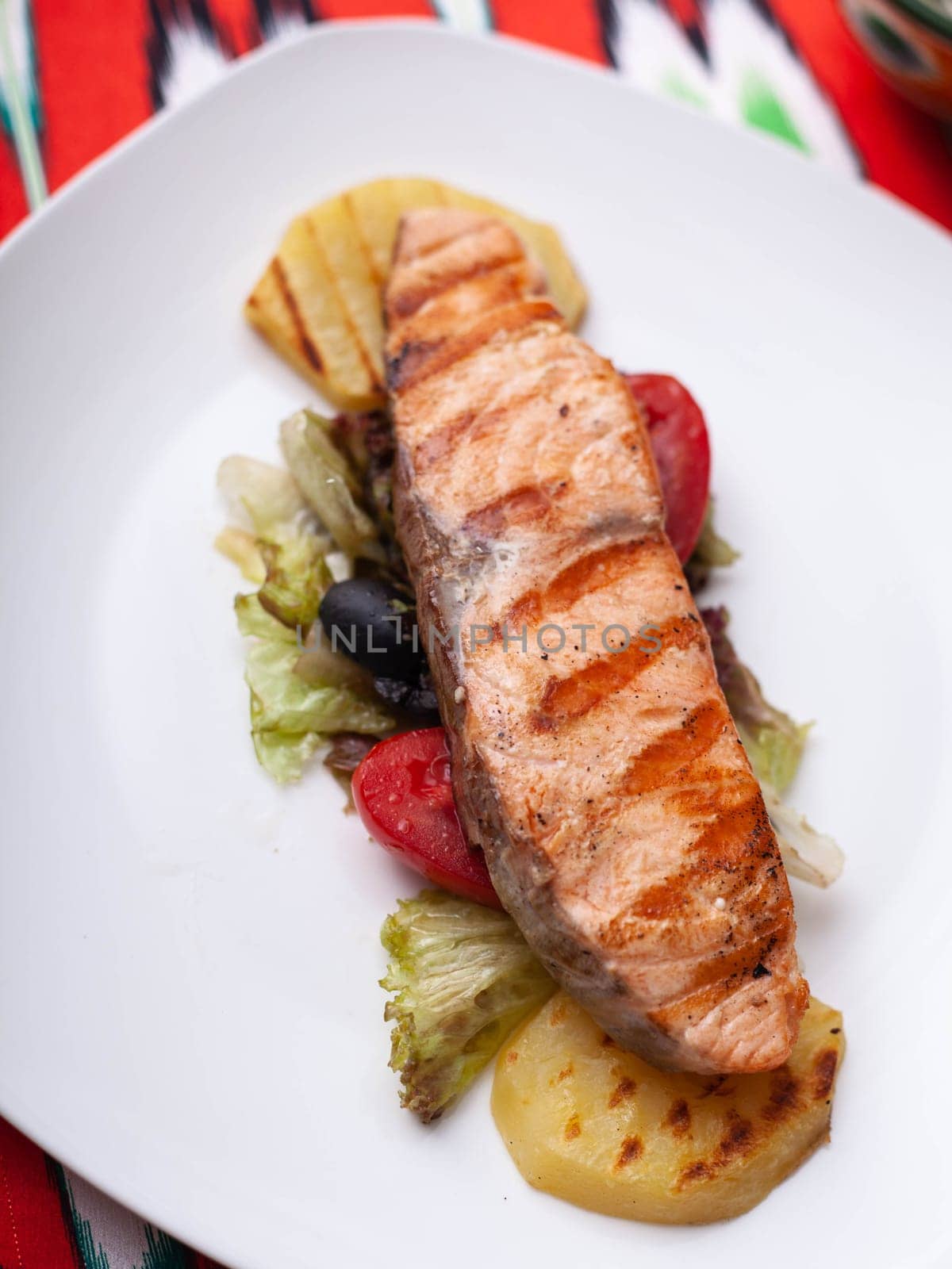 Salmon steak on a pillow of stewed vegetables. Asian style. High quality photo
