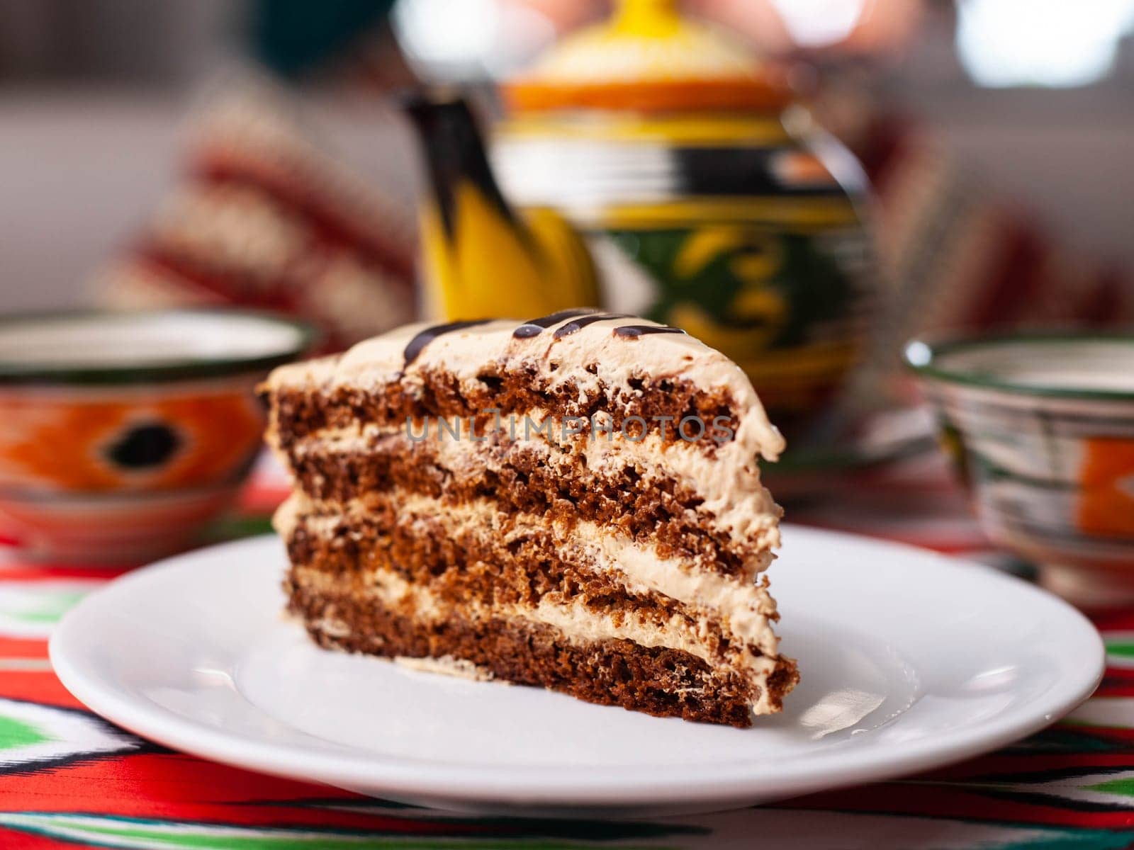 dessert chocolate cake with beige cream in oriental style on a rooftop with a teapot and a cup for tea. High quality photo