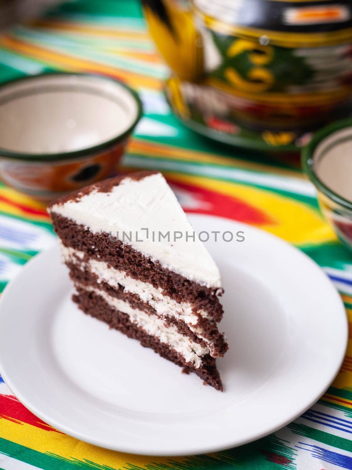 dessert chocolate cake with white butter cream in oriental style on a rooftop with a teapot and a cup for tea. High quality photo