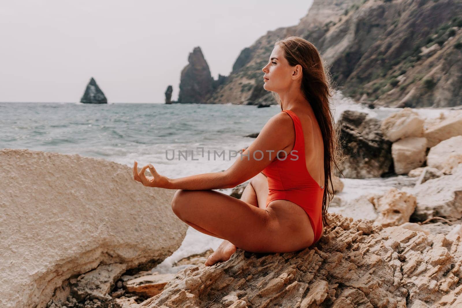 Woman sea yoga. Happy woman meditating in yoga pose on the beach, ocean and rock mountains. Motivation and inspirational fit and exercising. Healthy lifestyle outdoors in nature, fitness concept. by panophotograph