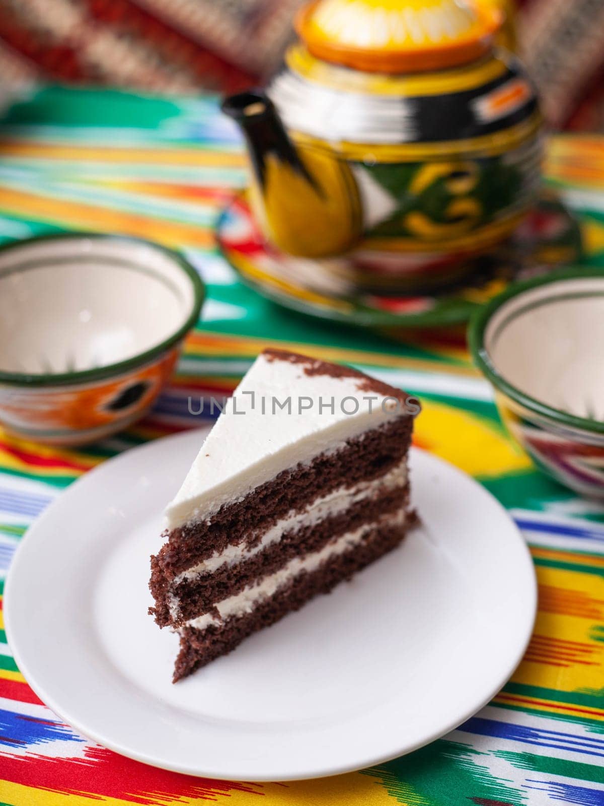 dessert chocolate cake with white butter cream in oriental style on a rooftop with a teapot and a cup for tea. High quality photo