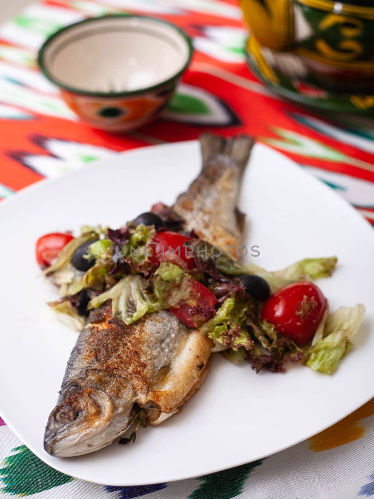 Fried fish with a pillow of stewed vegetables. Asian style. High quality photo