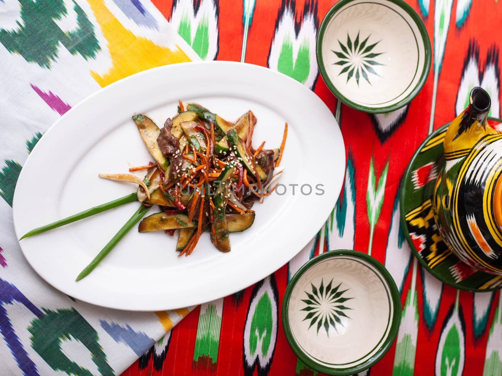 Eastern warm salad. Fried pieces of beef, marcovi and cucumbers in sauce and sesame seeds. Asian style. High quality photo