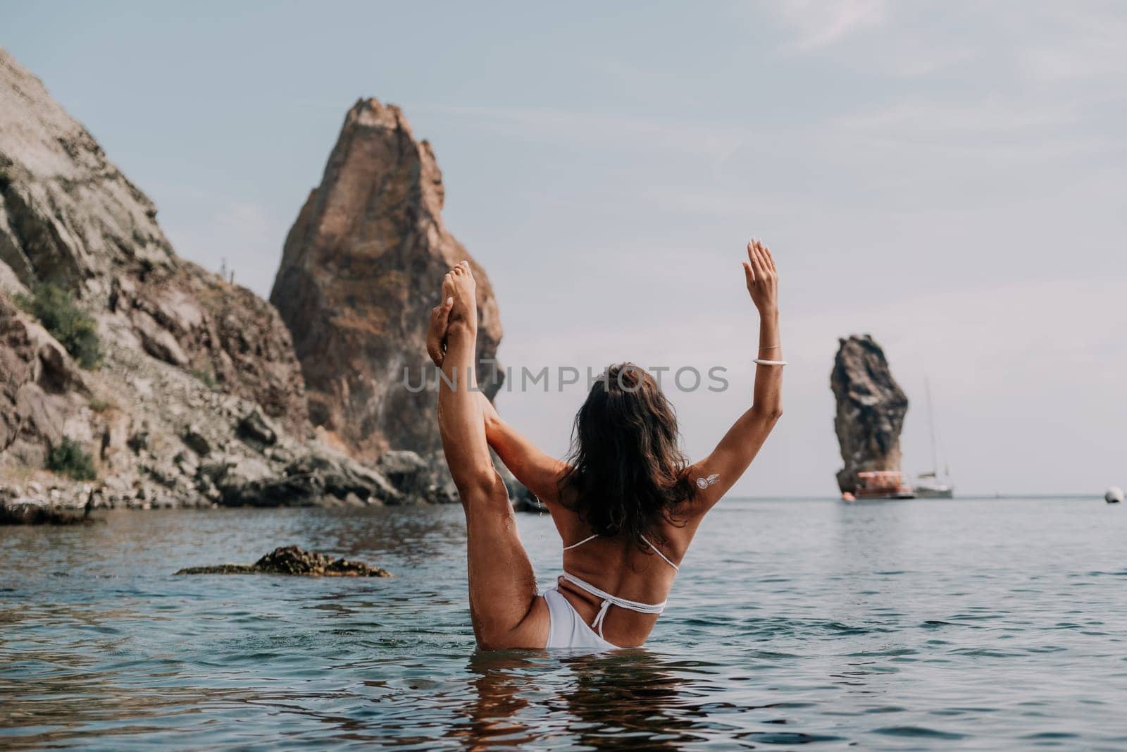 Woman sea fitness. Happy woman in a white bikini performing pilates in the sea on the beach. Female fitness yoga routine concept. Healthy lifestyle. by panophotograph