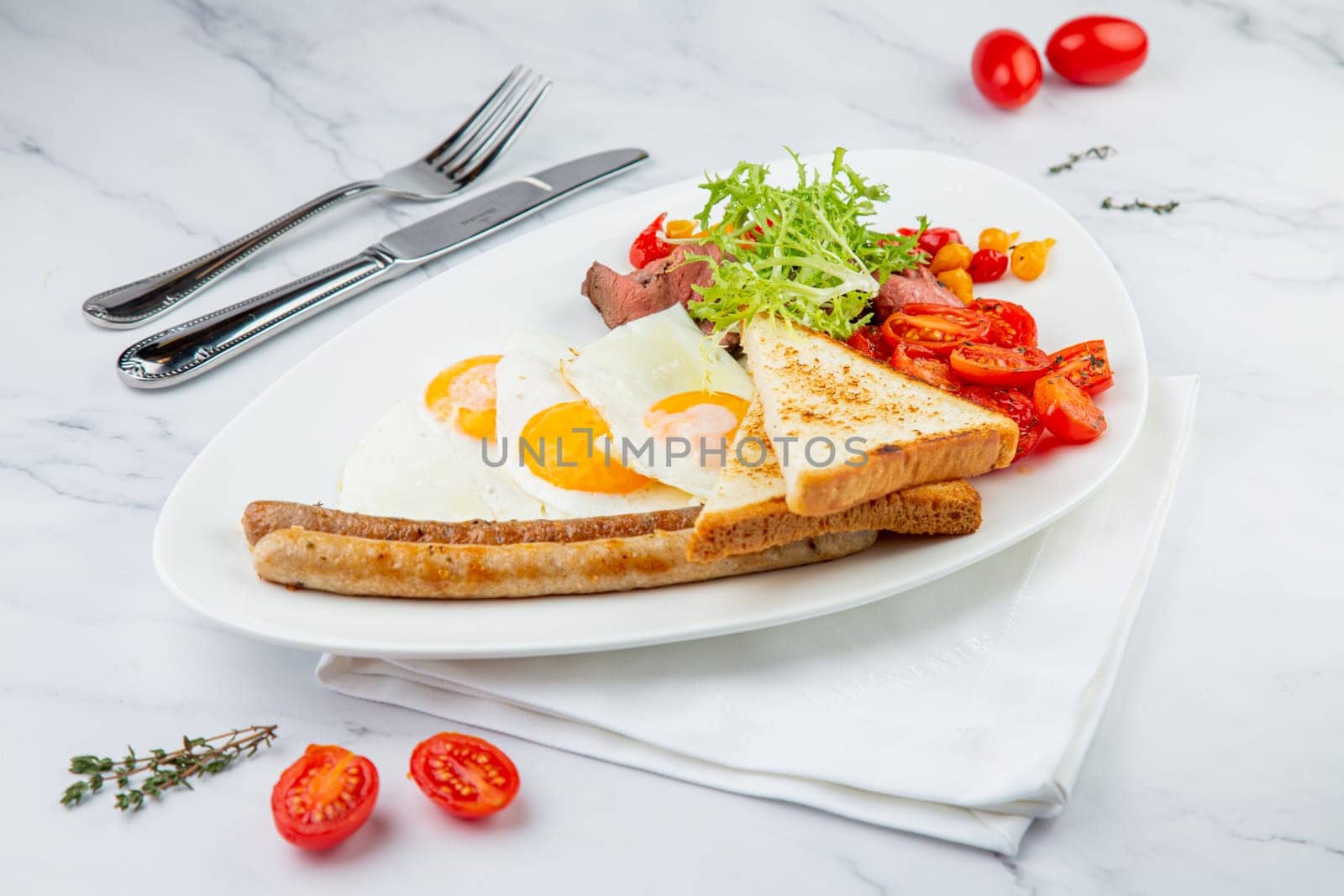 scrambled eggs with vegetables, cherry tomatoes, bread, herbs and sausages on a white plate side view by tewolf