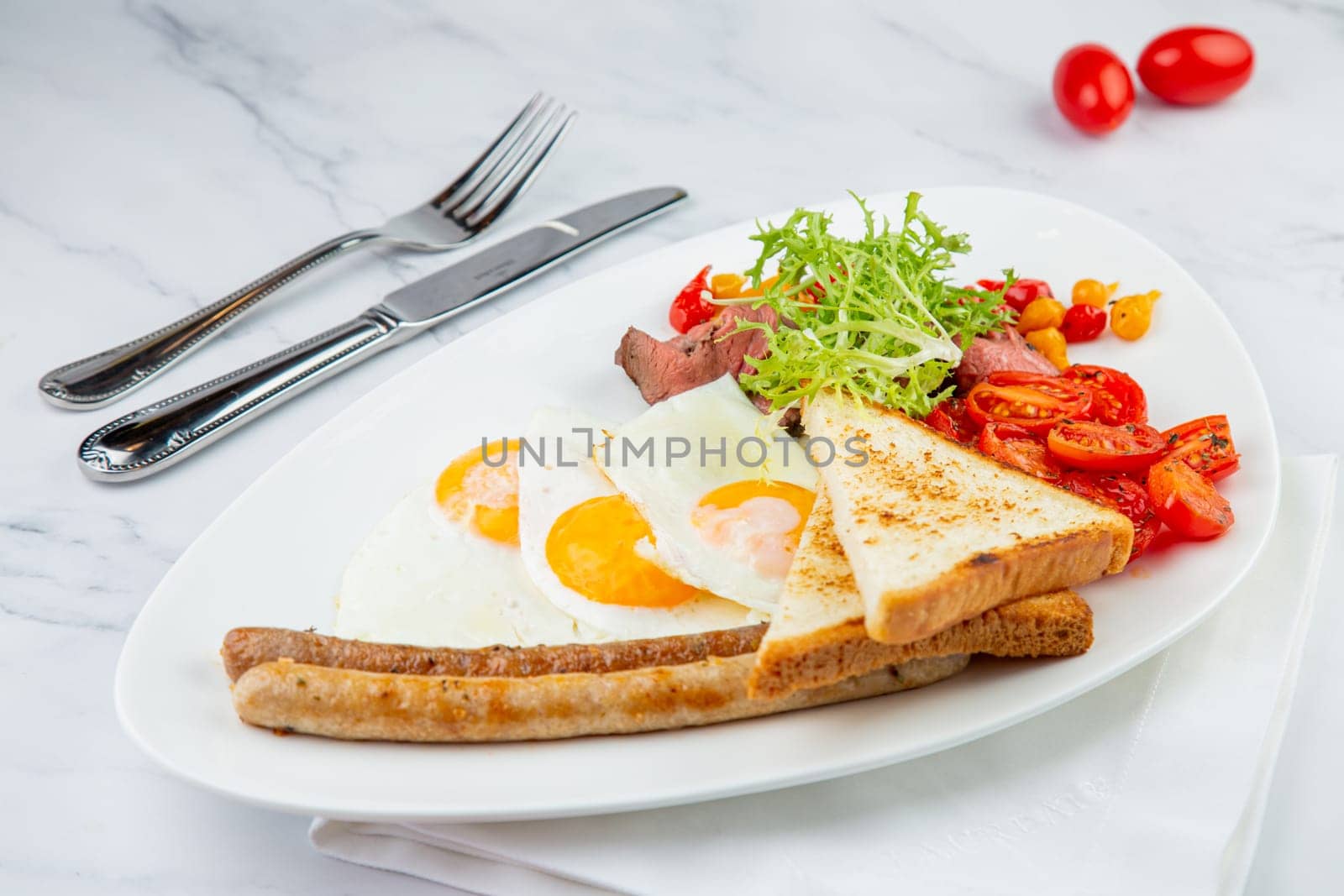 scrambled eggs with vegetables, cherry tomatoes, bread, herbs and sausages on a white plate side view by tewolf