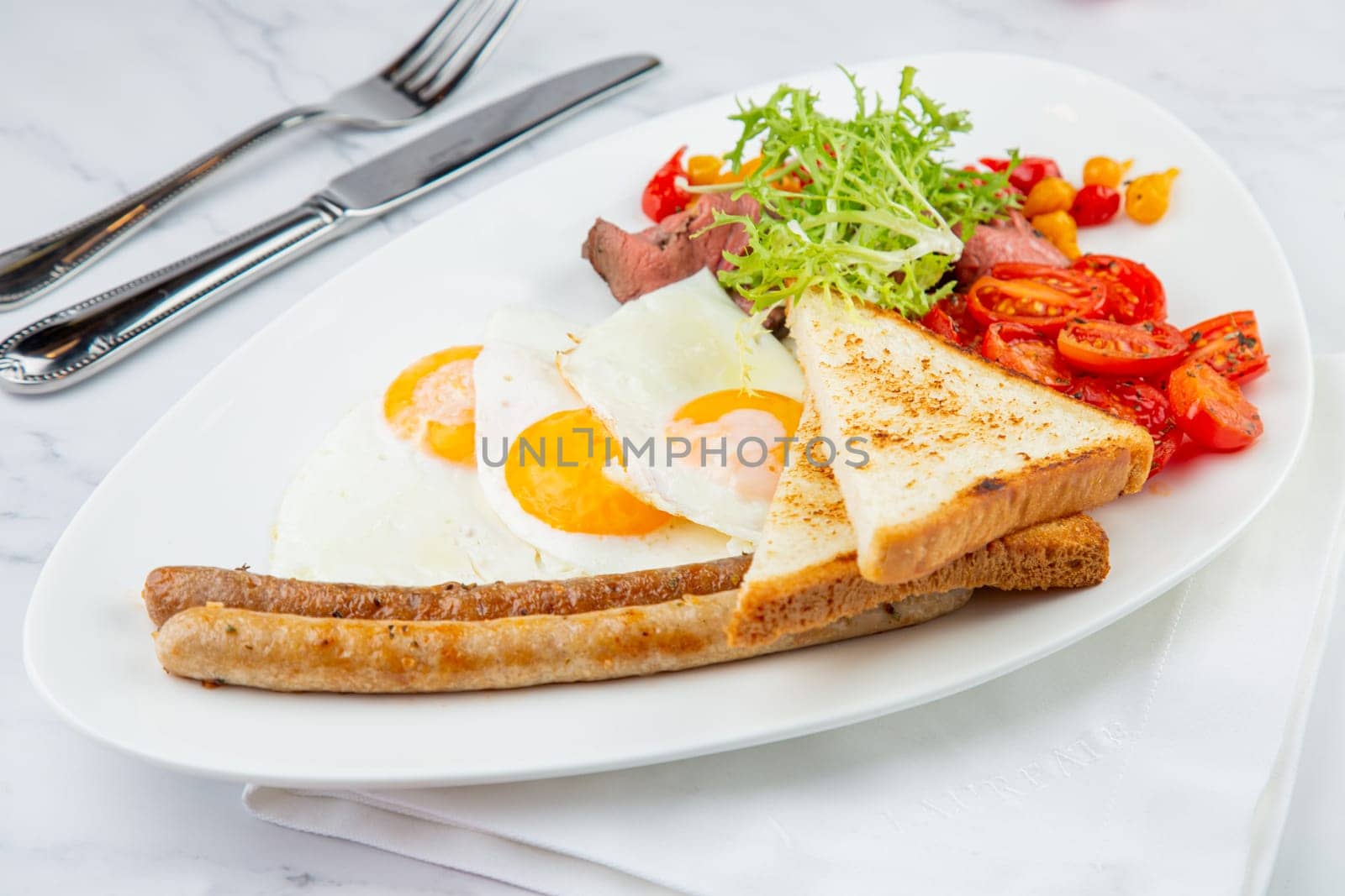 scrambled eggs with vegetables, cherry tomatoes, bread, herbs and sausages on a white plate side view by tewolf