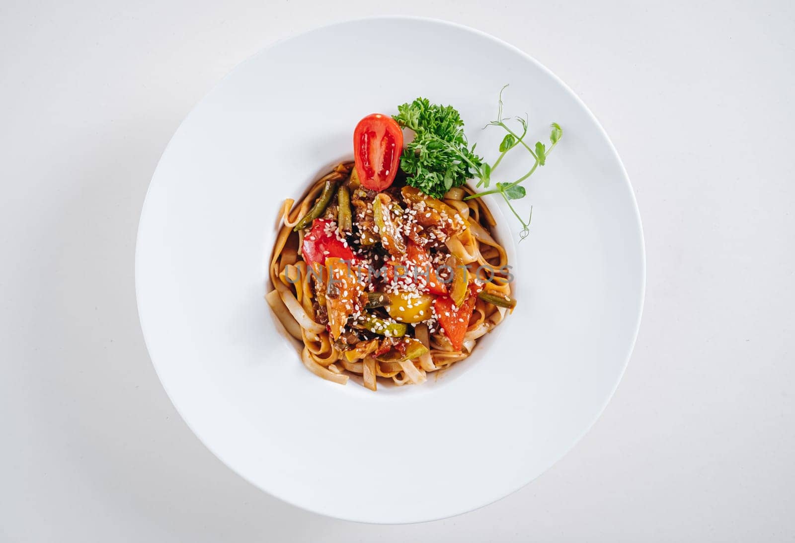 udon noodles with sesame seeds and herbs in a white plate top view by tewolf