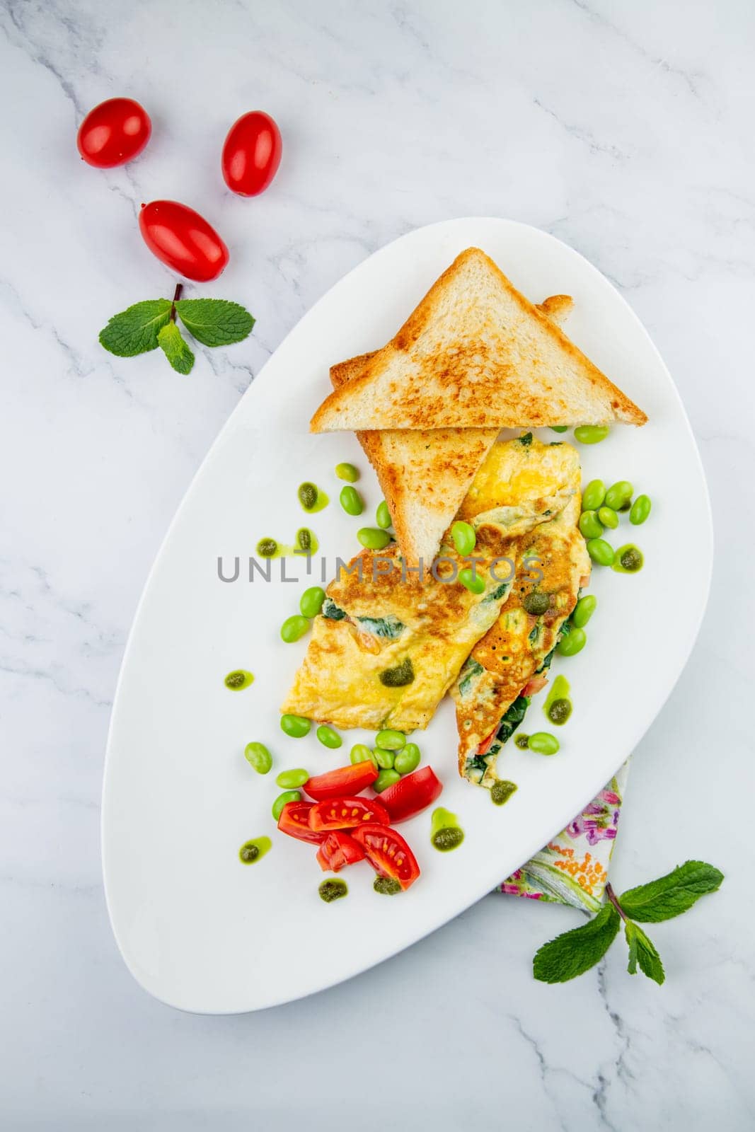 Breakfast of eggs and vegetables with cherry tomatoes and slices of bread in a white plate top view by tewolf