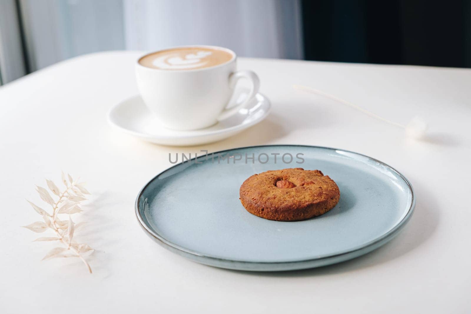 Cookies with nuts inside and coffee with a pattern on a round plate top view by tewolf