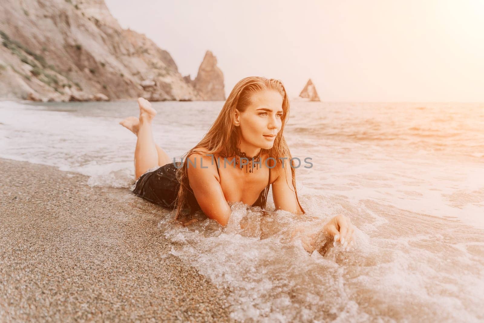 Woman summer travel sea. Happy tourist in black dress enjoy taking picture outdoors for memories. Woman traveler posing on sea beach surrounded by volcanic mountains, sharing travel adventure journey by panophotograph