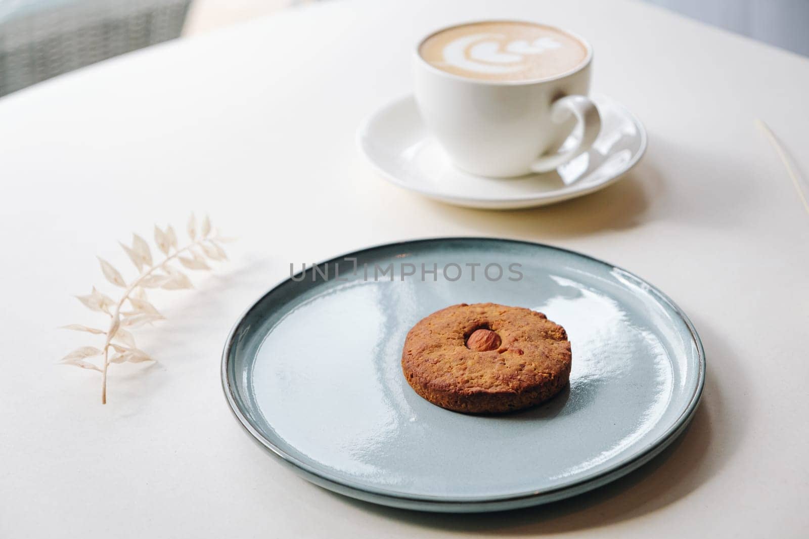 Cookies with nuts inside and coffee with a pattern on a round plate top view by tewolf