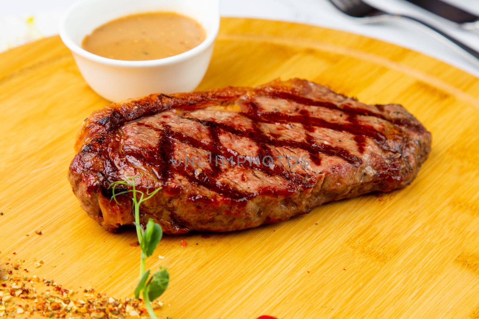 beef steak with spices and sauce on a wooden tray side view by tewolf