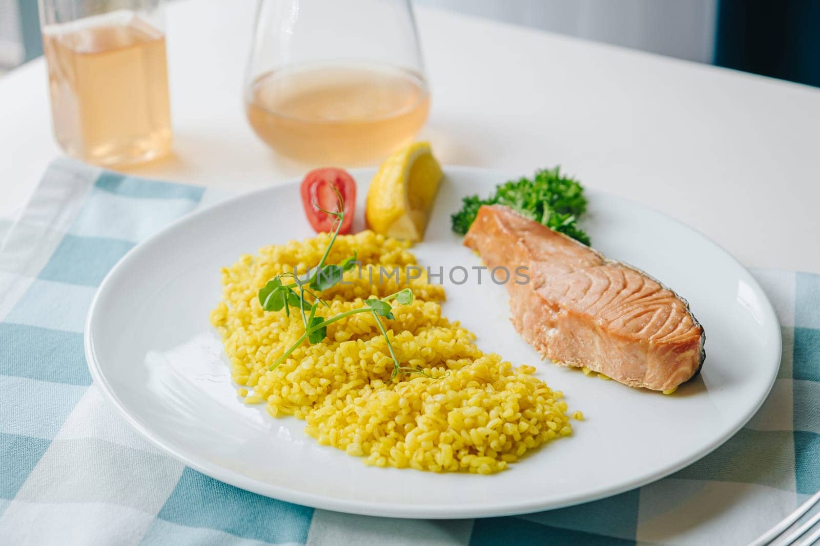 proper nutrition, daily diet, weight loss. greens, tomatoes, salmon steak with lemon and couscous garnish on a plate.