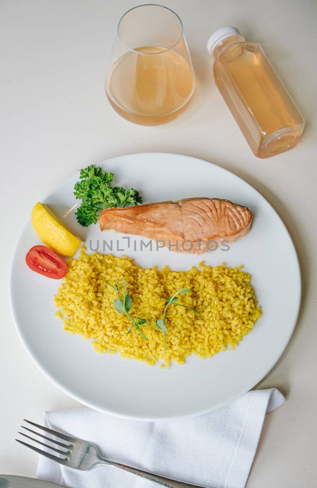proper nutrition, daily diet, weight loss. greens, tomatoes, salmon steak with lemon and couscous garnish on a plate.