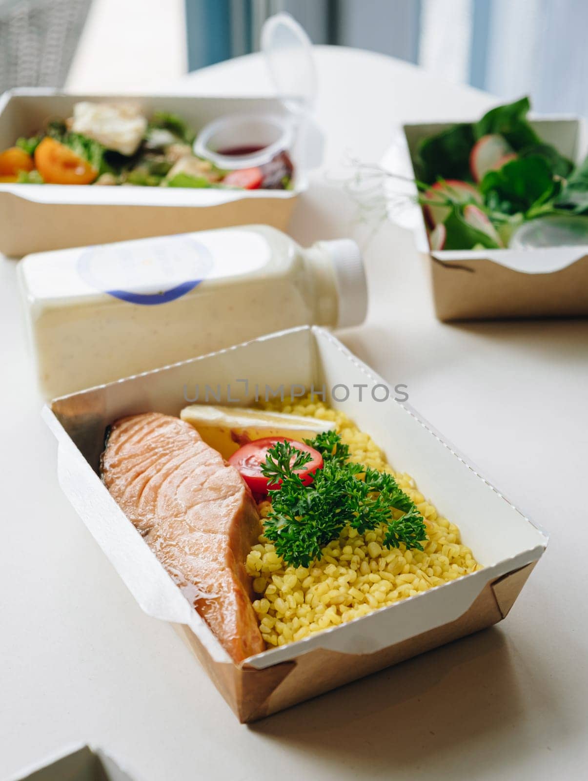 food in containers. proper nutrition, daily diet, weight loss. greens, tomato, lemon salmon steak with couscous side dish.