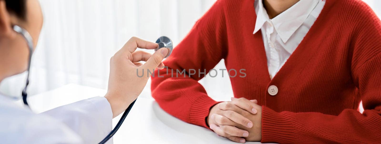 Patient attend doctor's appointment at clinic or hospital office. Doctor examining and diagnosis symptoms while checking the patient's pulse with stethoscope. Panorama Rigid