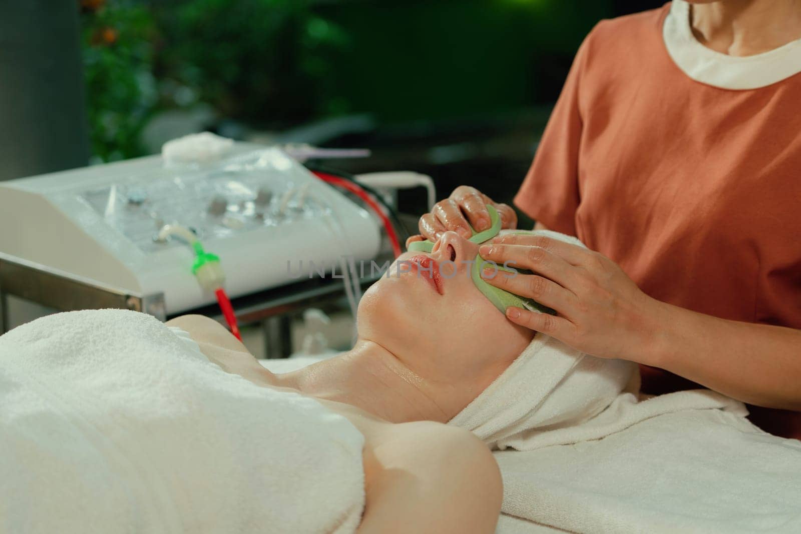 Attractive caucasian woman receive electrical facial treatment. Beautiful girl lies on spa bed while having medical treatment from professional doctor from medical spa center. Tranquility.