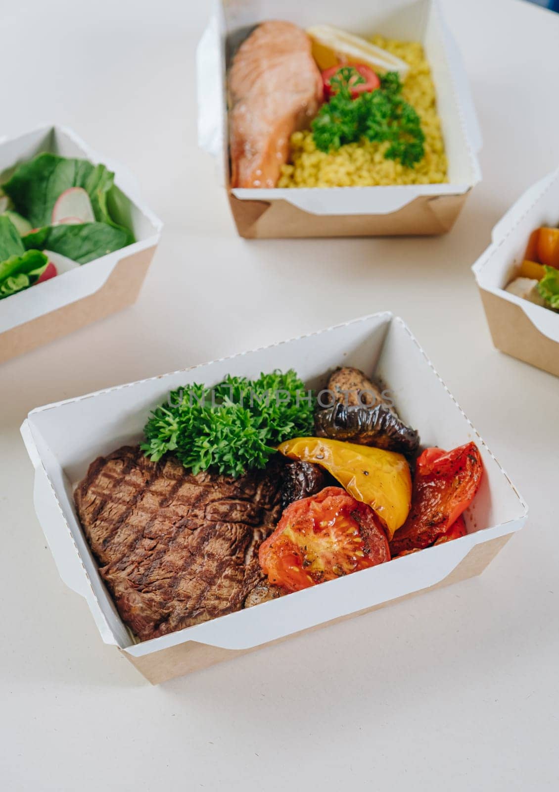 food in containers. proper nutrition, daily diet, weight loss. drink, veal steak with grilled vegetables, salmon steak with couscous side dish.