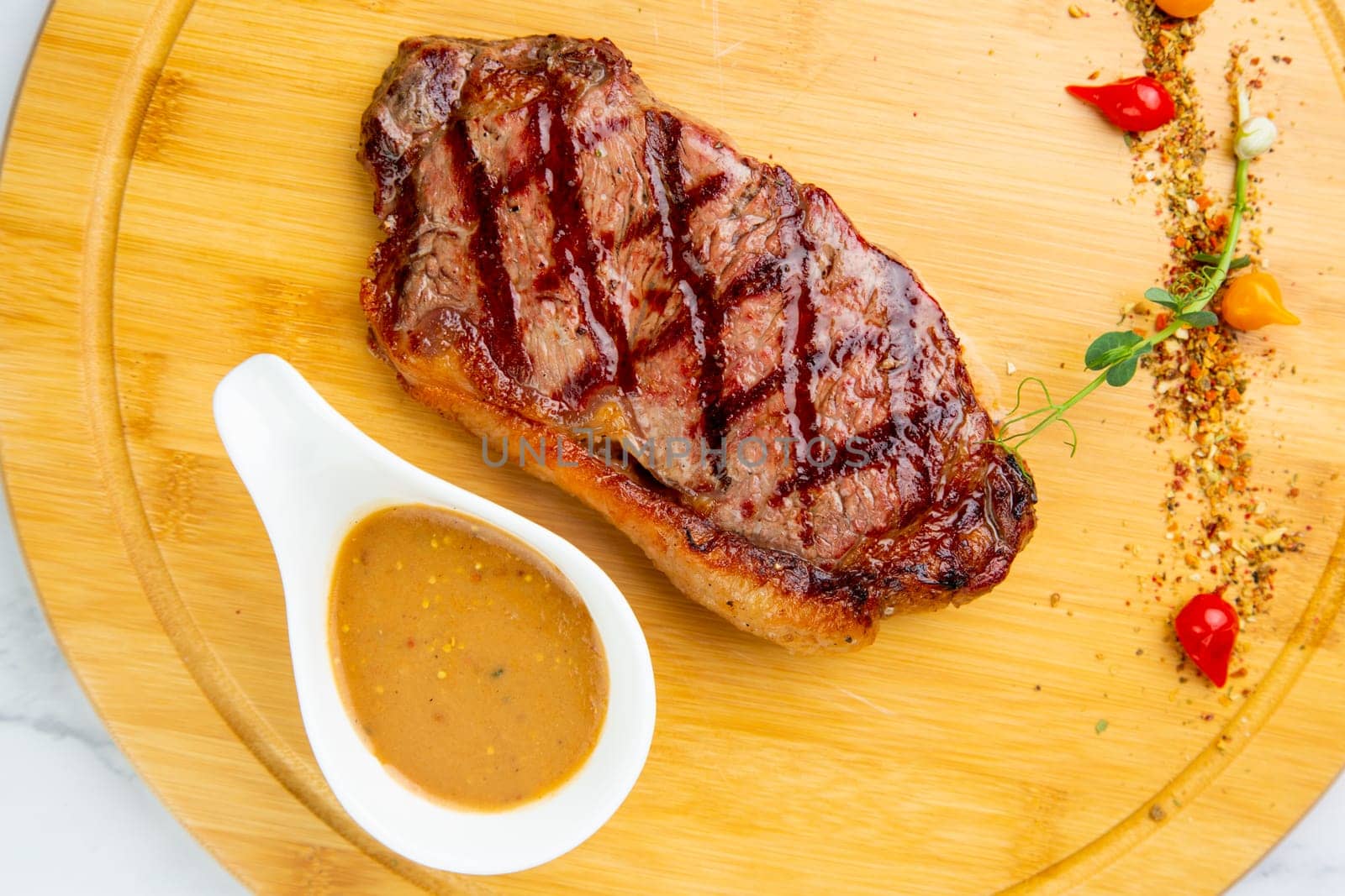 beef steak with spices and sauce on a wooden tray side view by tewolf