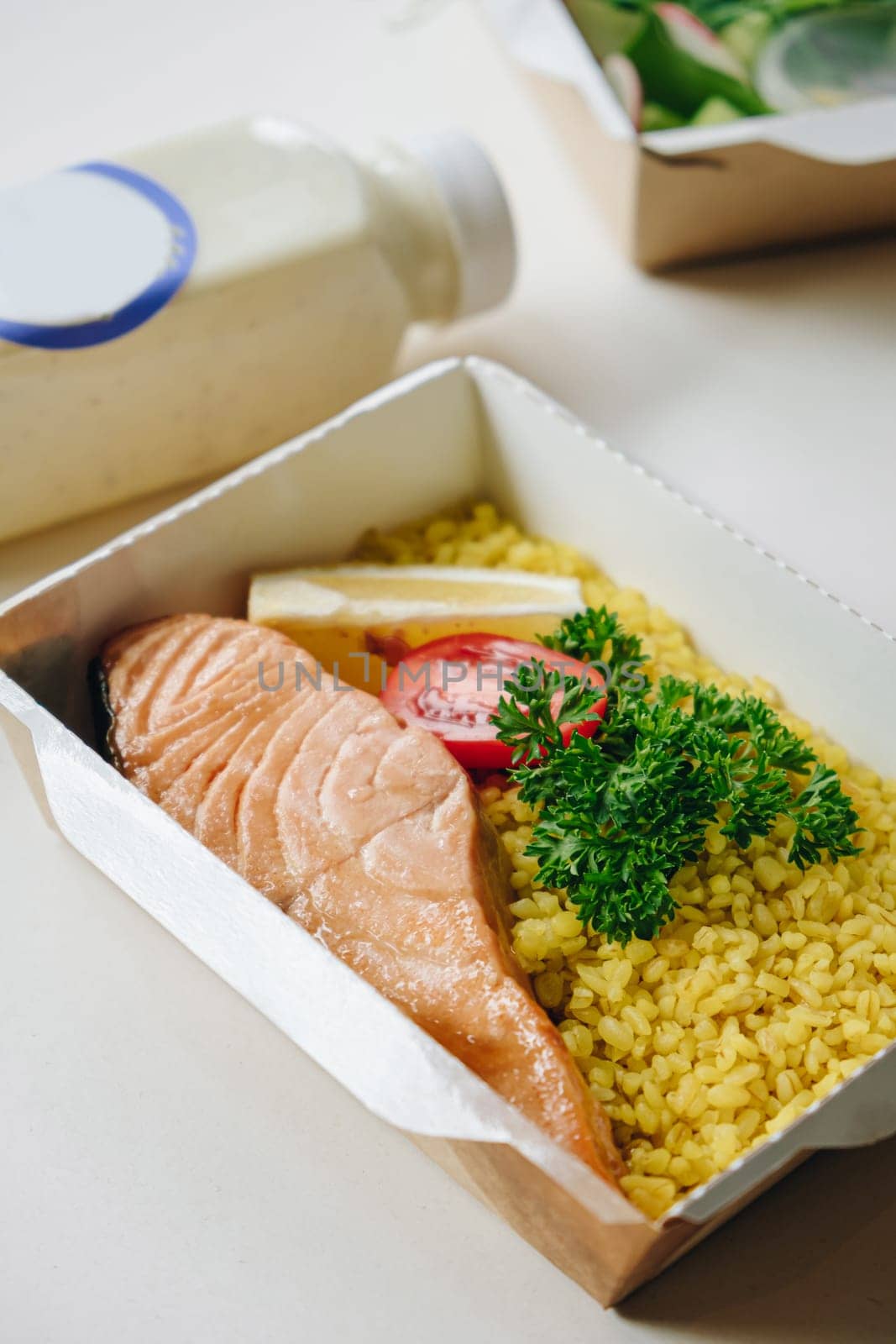 food in containers. proper nutrition, daily diet, weight loss. greens, tomato, lemon salmon steak with couscous side dish.