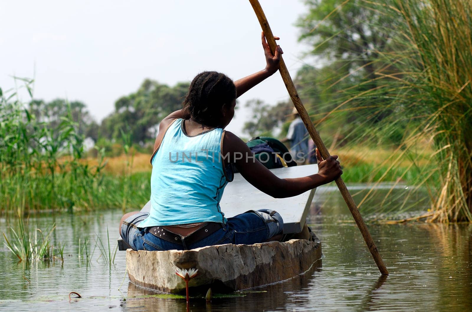 Young woman in mokoro dugout canoe returning to village from shopping in the city,Okavango Delta,Botswana
