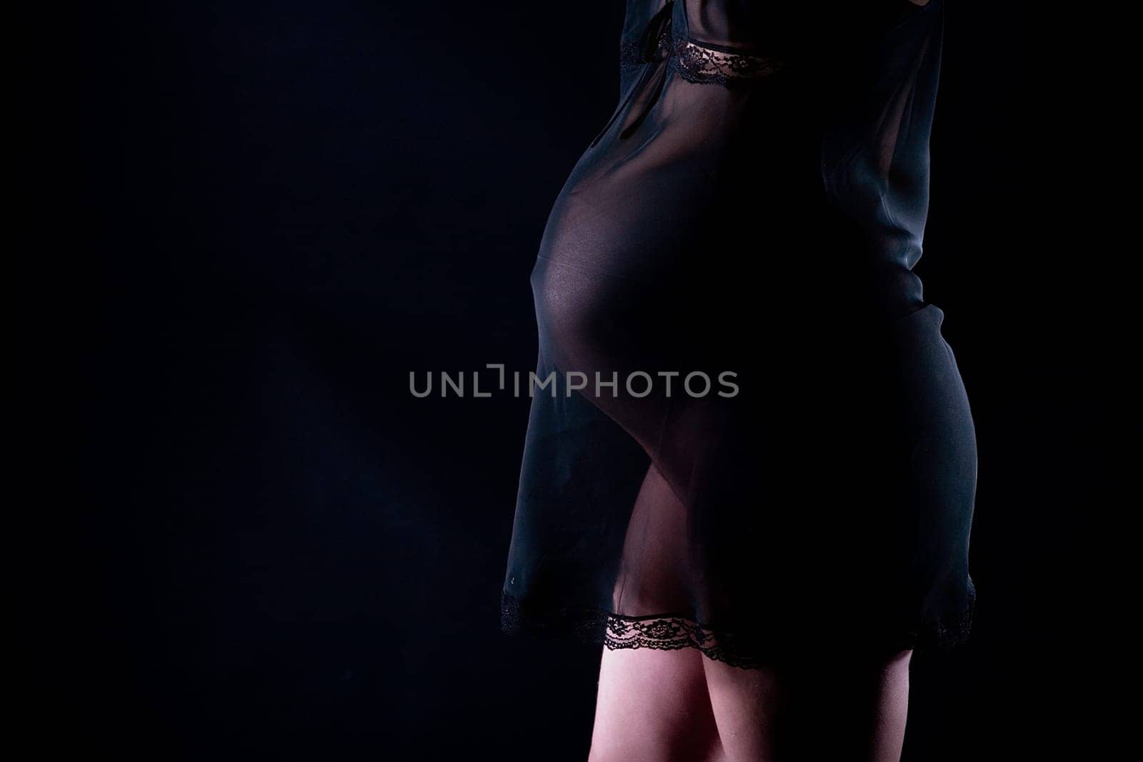 Pregnant attractive woman (8th month) in see-through dress. Black background.