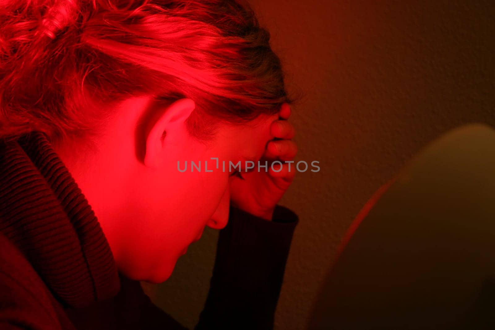 Young woman is irradiated by red light
