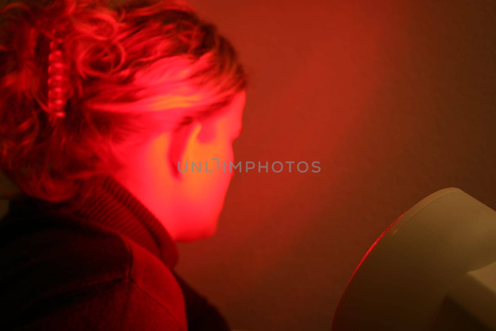 Young woman is irradiated by red light