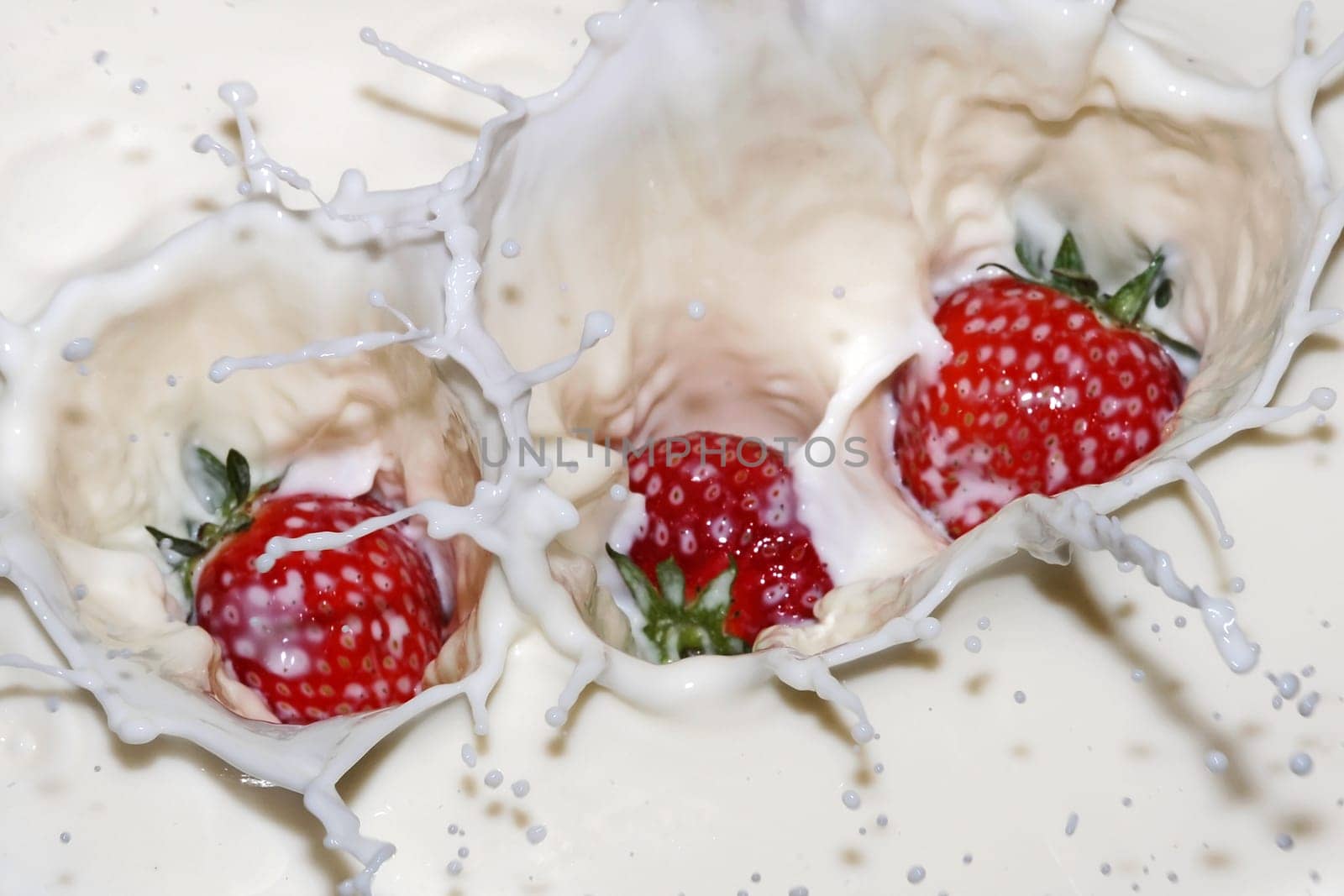Strawberries fall into milk