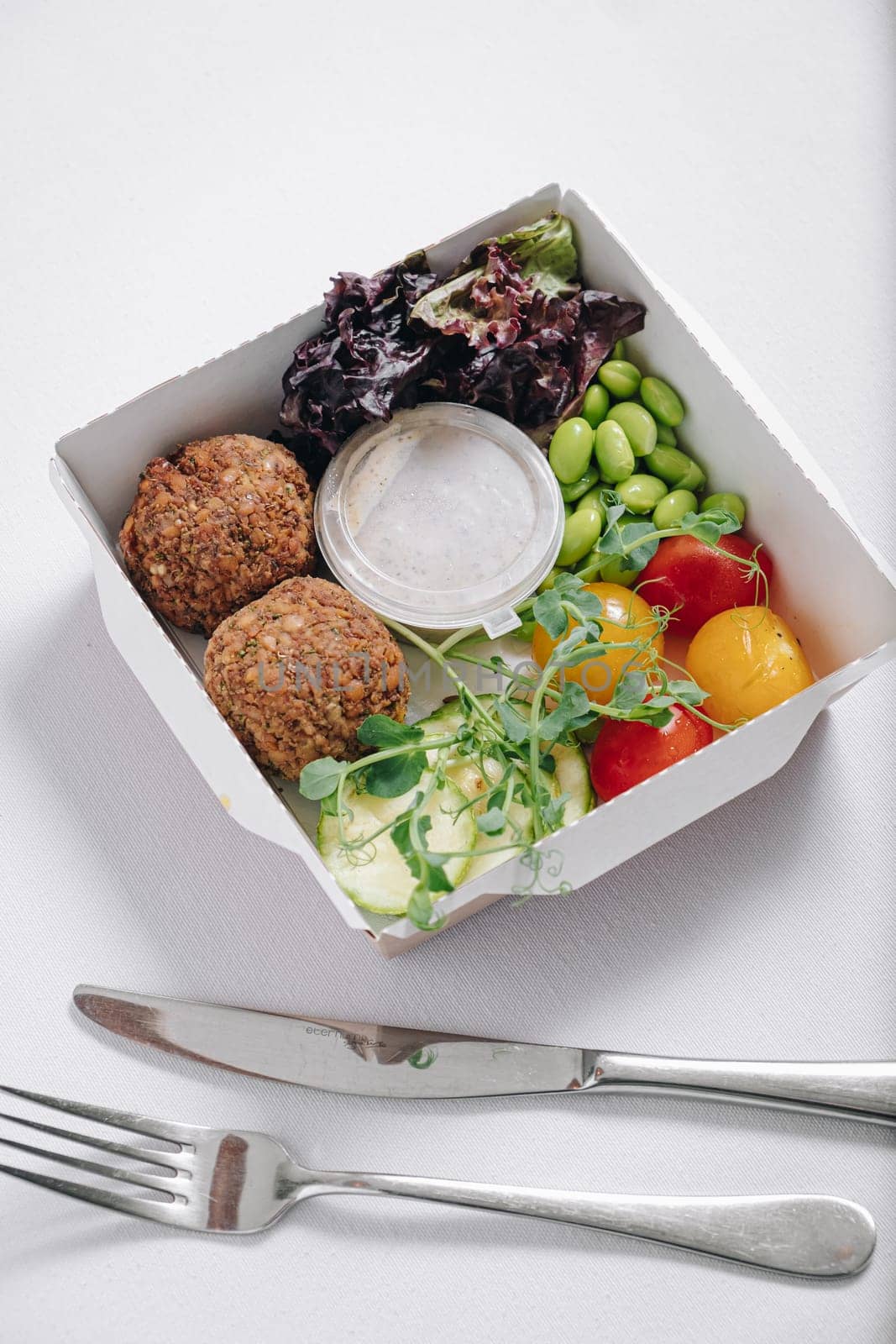 bowl in Chinese style.meatballs with beans, herbs, cherry tomatoes and sauce in a container top view by tewolf