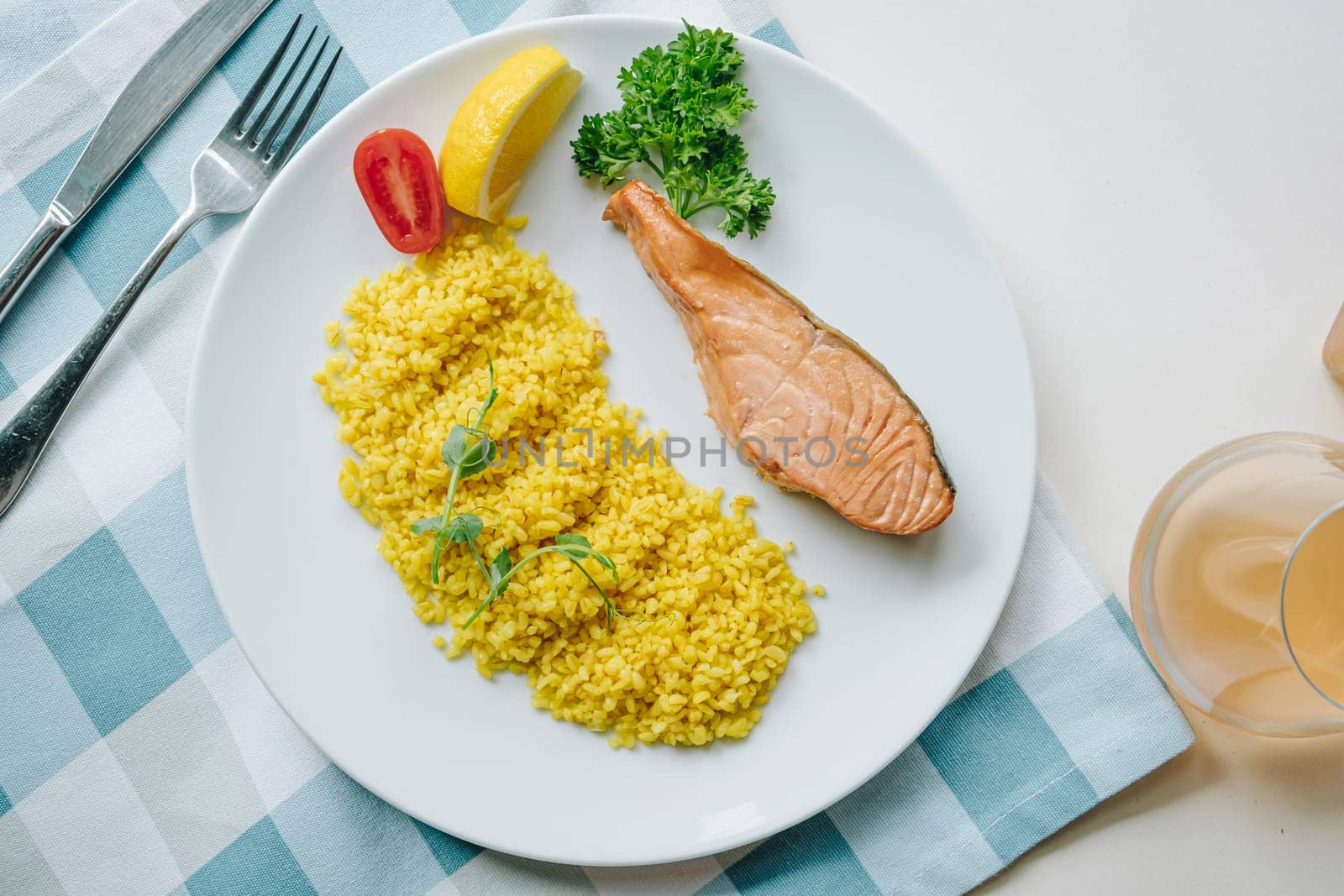 proper nutrition, daily diet, weight loss. greens, tomatoes, salmon steak with lemon and couscous garnish on a plate. Top view by tewolf