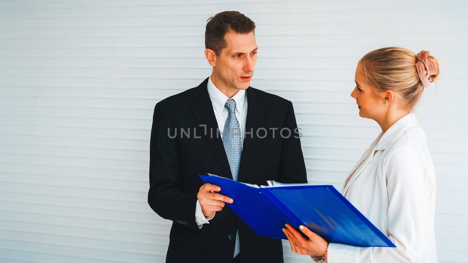 Two business people talk project strategy at office meeting room. Businessman discuss project planning with colleague at modern workplace while having conversation and advice on financial report. Jivy