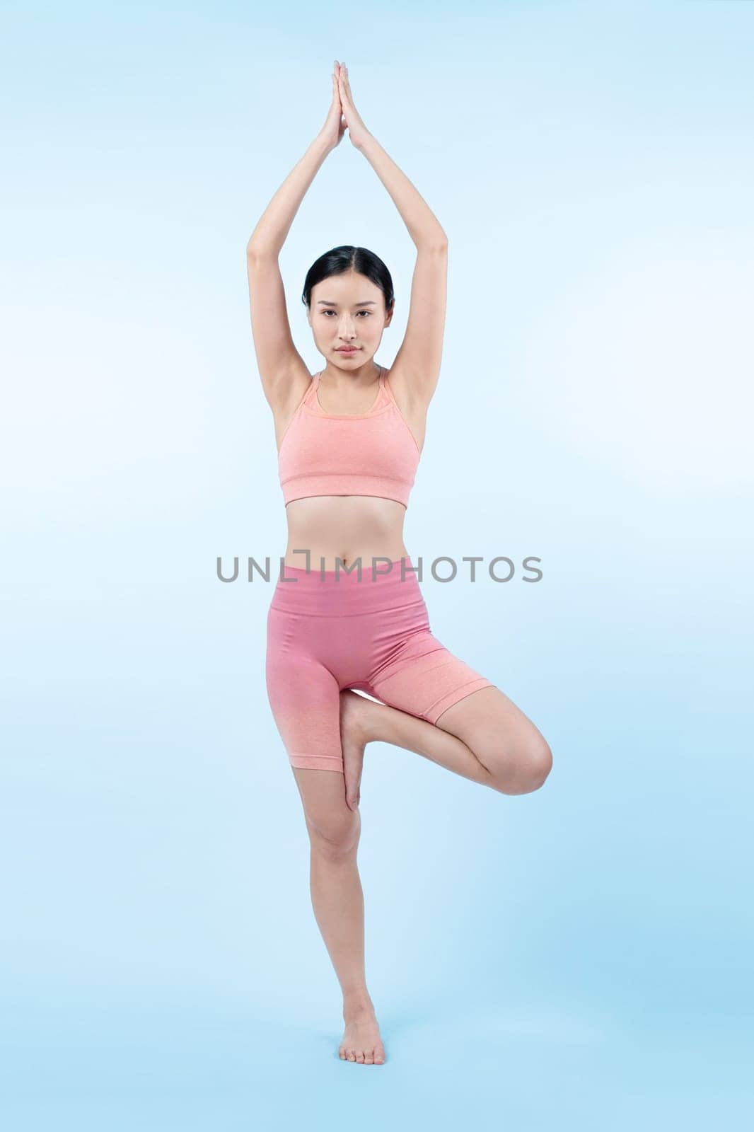 Asian woman in sportswear doing yoga exercise in standing pose on fitness as her workout training routine. Healthy body care and meditation yoga lifestyle in full shot on isolated background. Vigorous