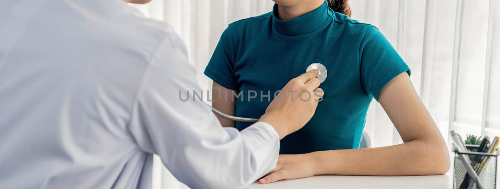 Patient attend doctor's appointment at clinic or hospital office. Doctor examining and diagnosis symptoms while checking the patient's pulse with stethoscope. Panorama Rigid