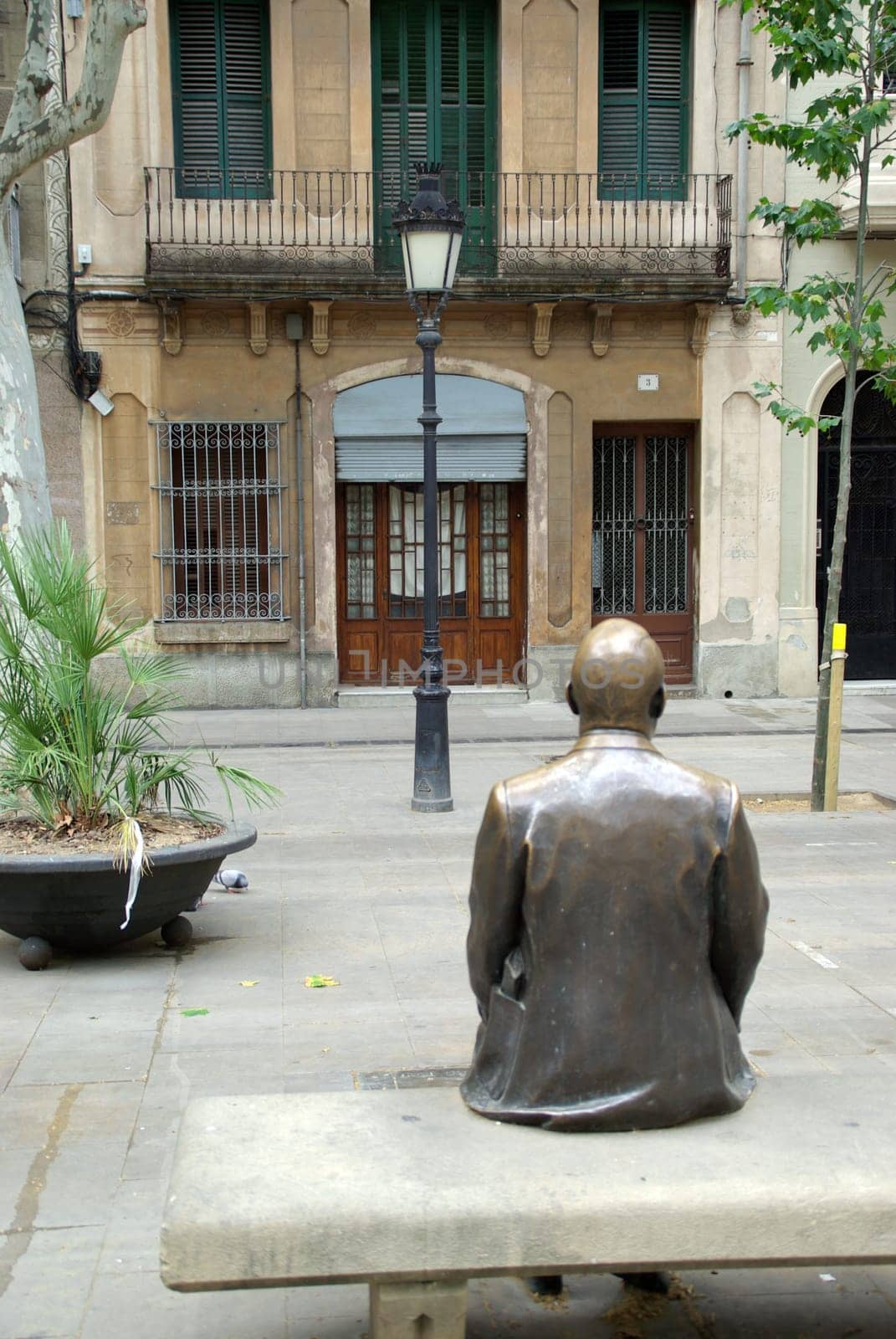 Figure on bench in front of house in a square in Barcelona