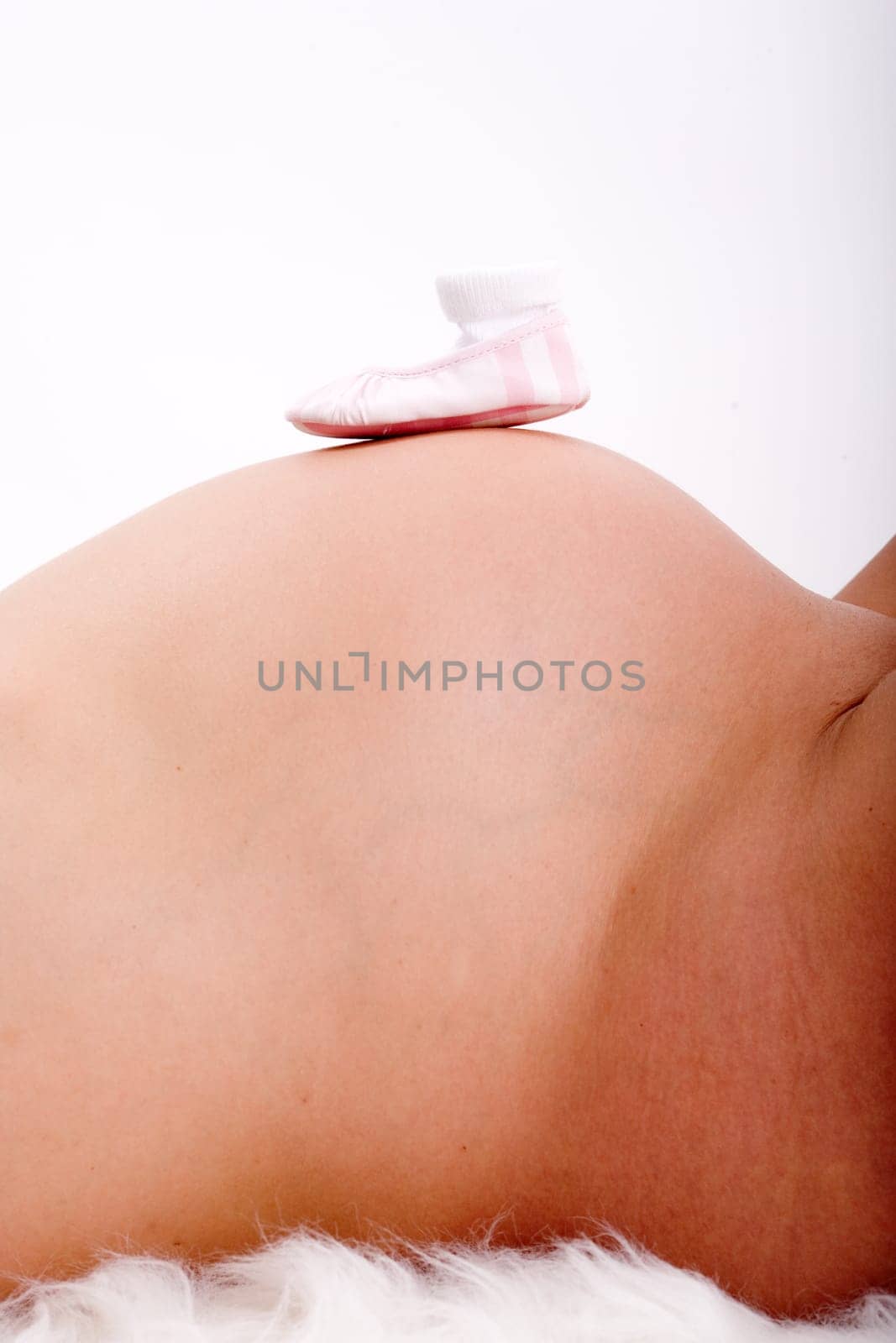 Pink baby shoes on mother's belly