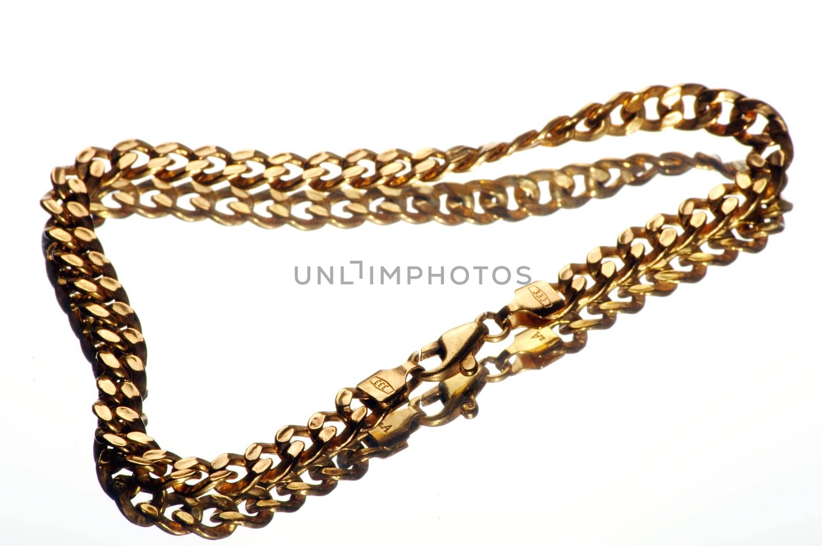a gold bracelet on a mirror plate exposed against a white background