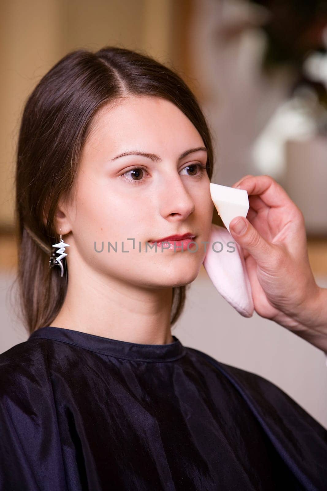 Woman during make-up by make-up artist