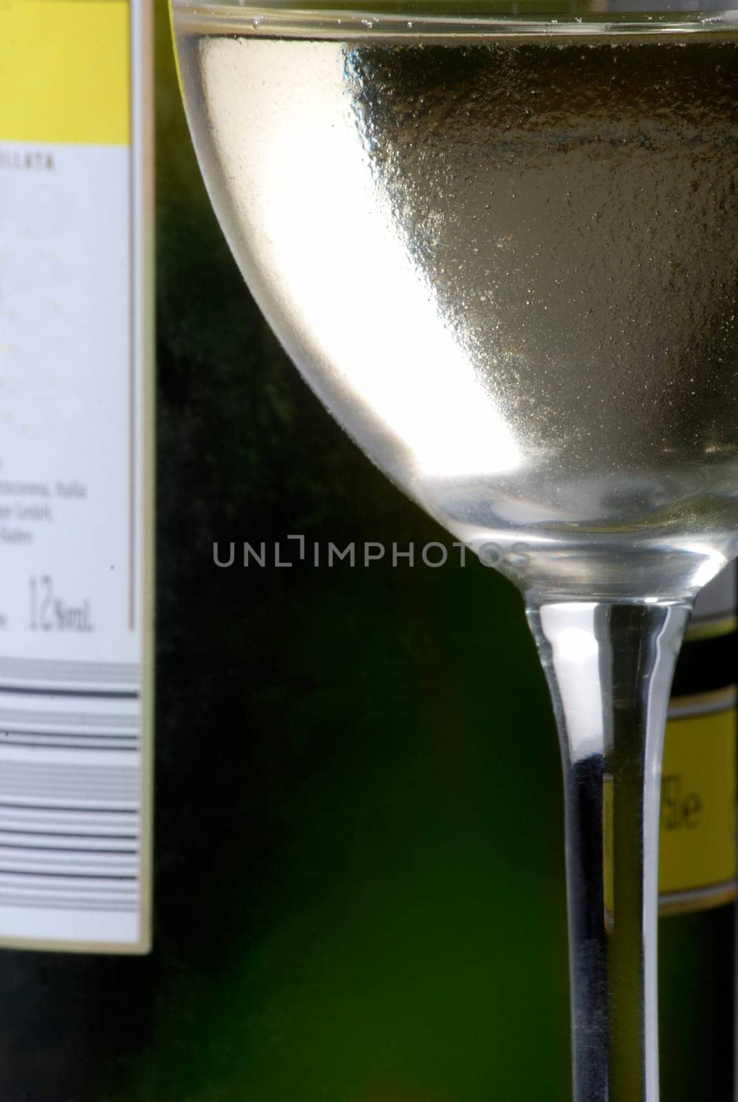 Cold wine glass in front of wine bottle