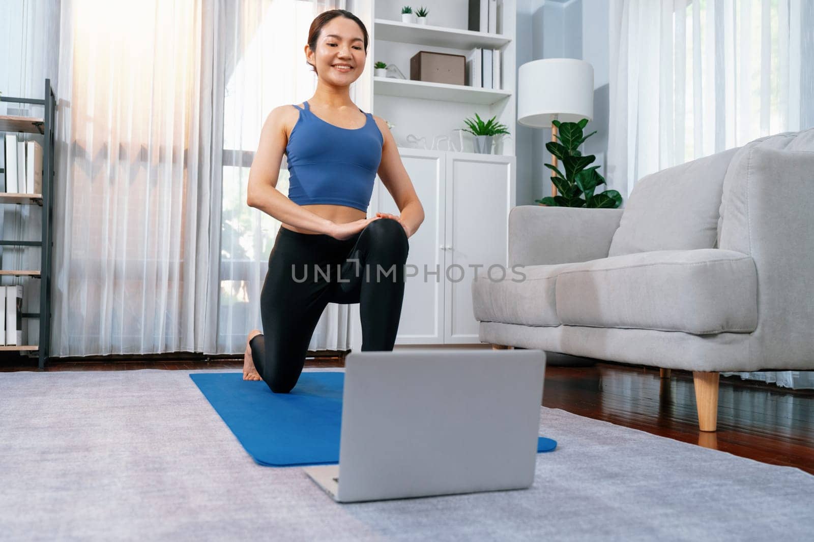 Asian woman in sportswear and yoga exercise on fitness mat with laptop. Vigorous by biancoblue