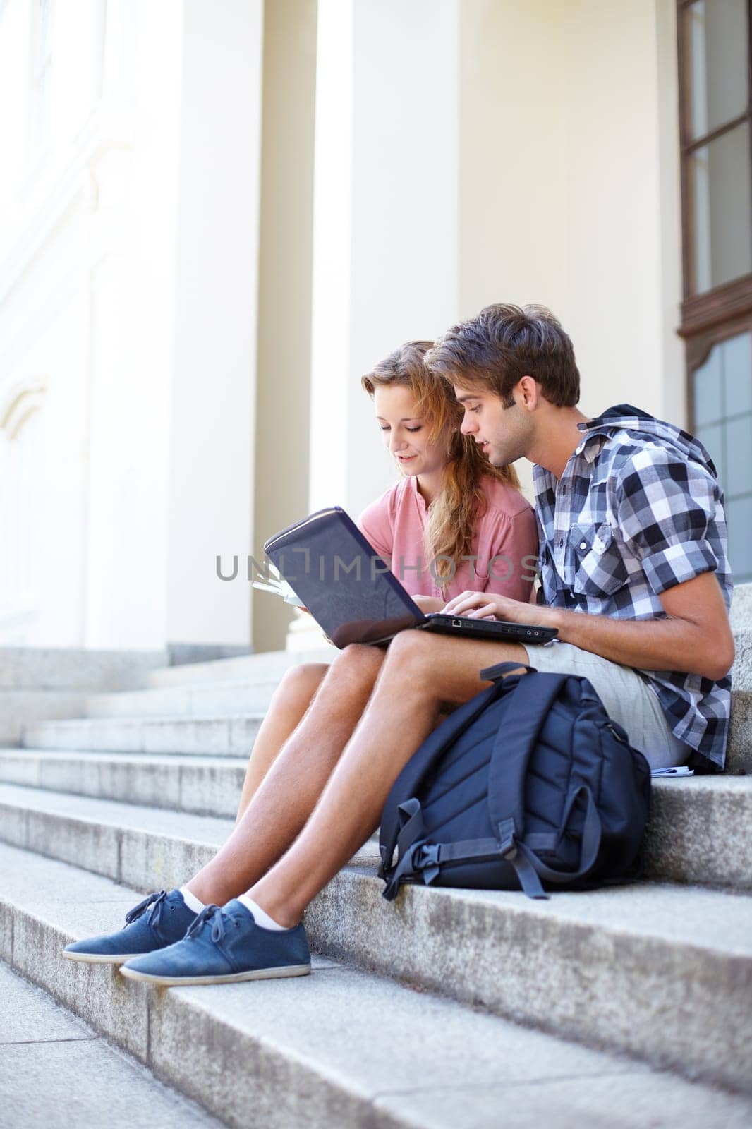 University, education and students with laptop on building steps for team project research. Learning, studying and gen z friends online on stairs with book for assignment, exam or homework discussion by YuriArcurs