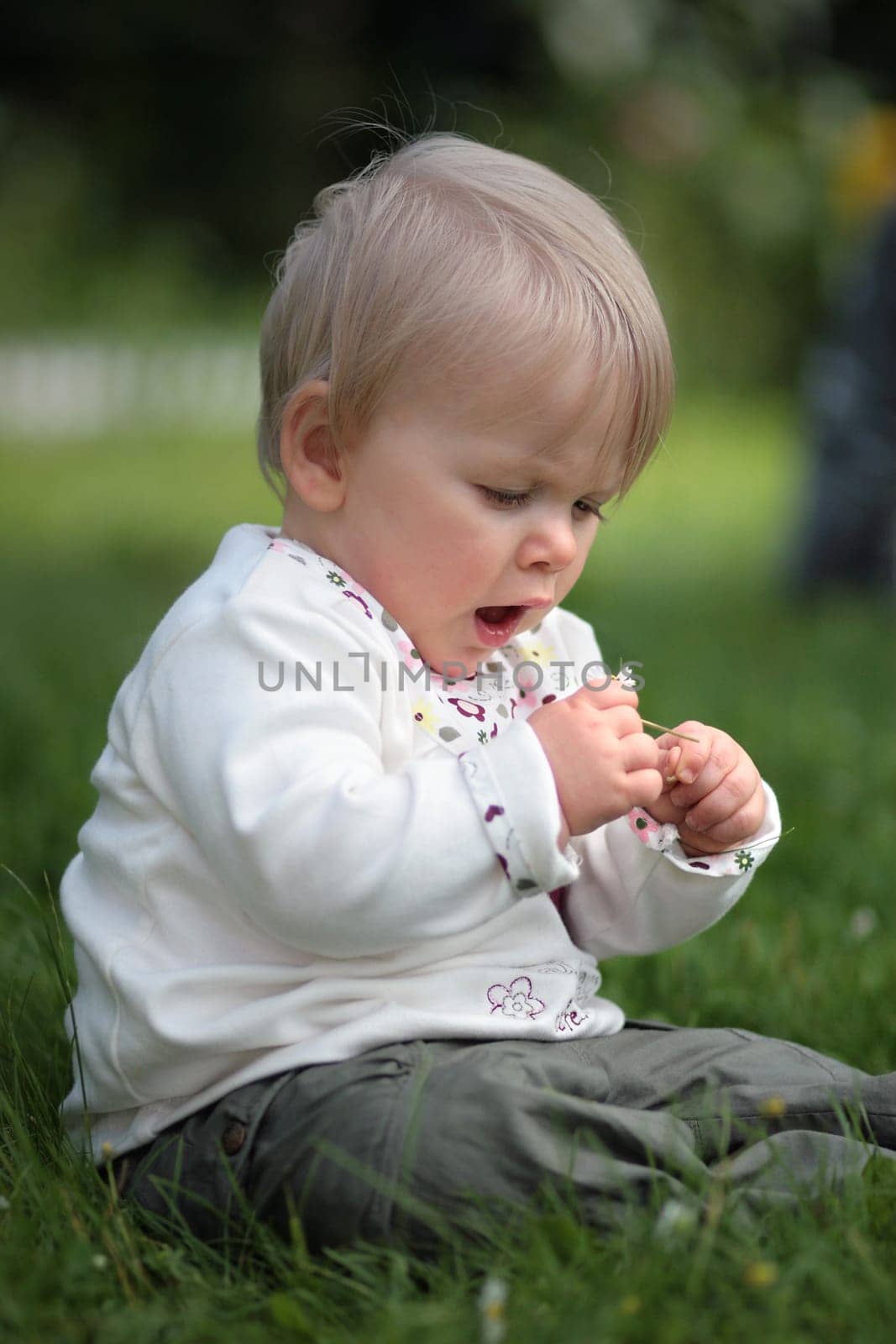 Baby looks at a flower in amazement
