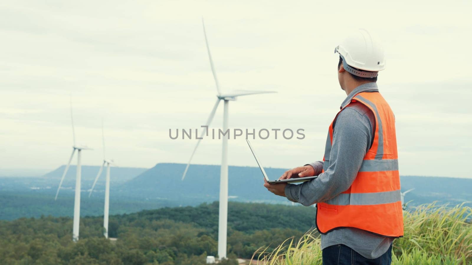 Engineer working on a wind farm atop a hill or mountain in the rural. Progressive ideal for the future production of renewable, sustainable energy. Energy generation from wind turbine.