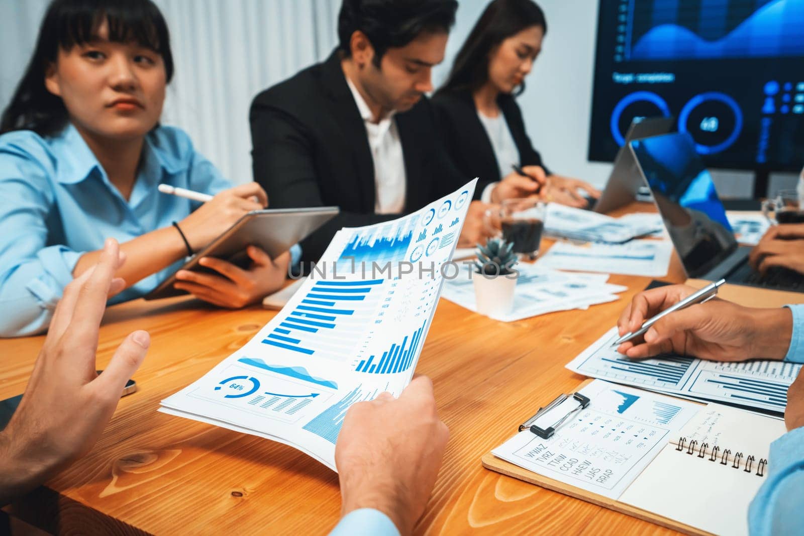 Diverse group of business analyst team analyzing financial data report. Finance data analysis chart and graph dashboard show on TV screen in meeting room for strategic marketing planning. Habiliment