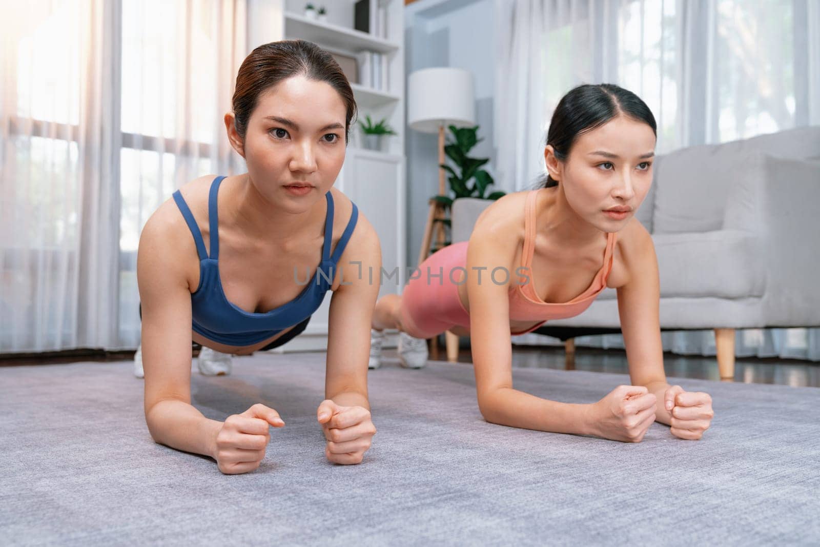 Fit young asian woman planing on the living room floor with her trainer or exercise buddy. Healthy lifestyle workout training routine at home. Balance and endurance exercising concept. Vigorous