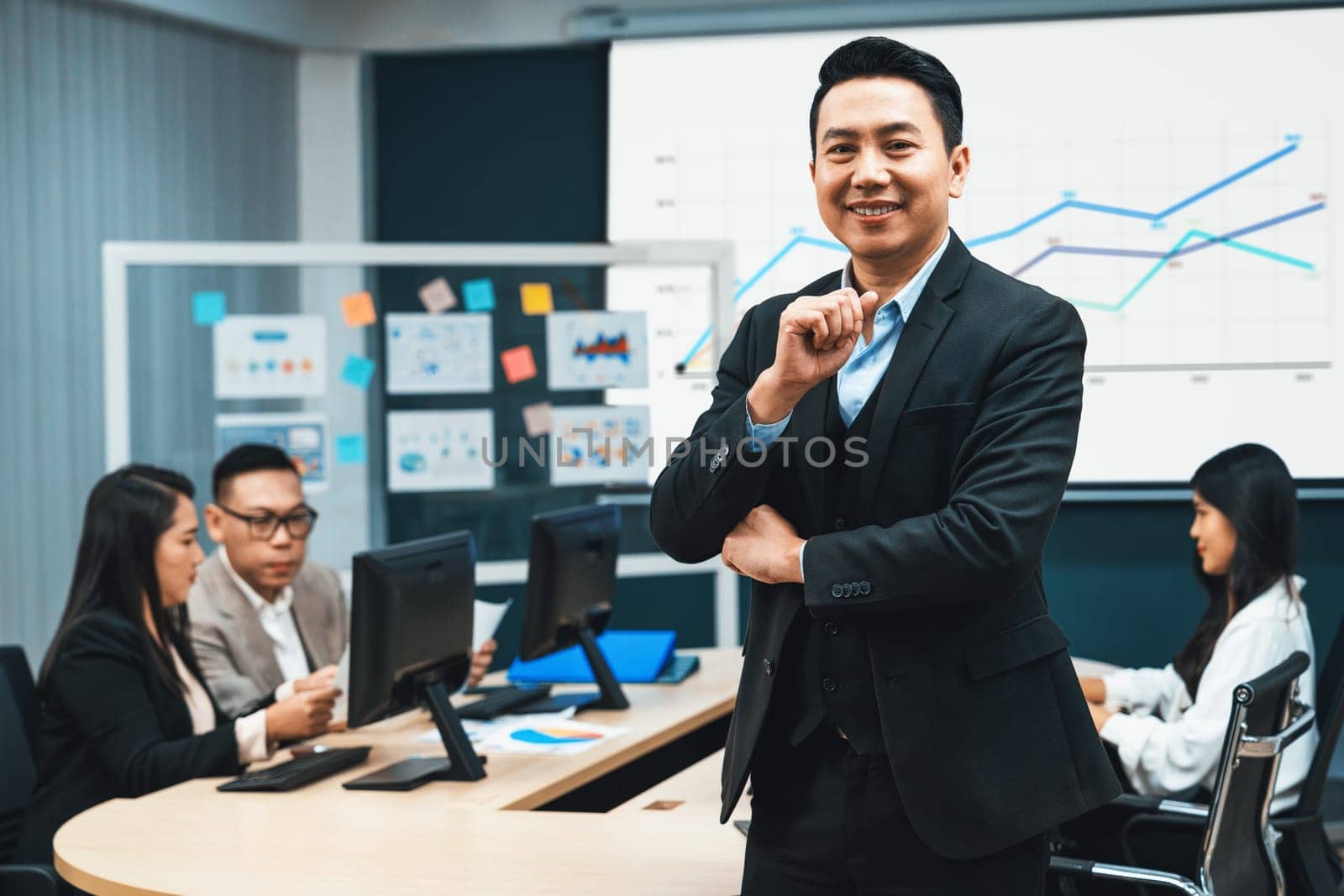 Successful businessman standing with arms crossed with confident. Intellectual. looking at camera. serious professional managers discussing about investment behind. conference room. Intellectual.