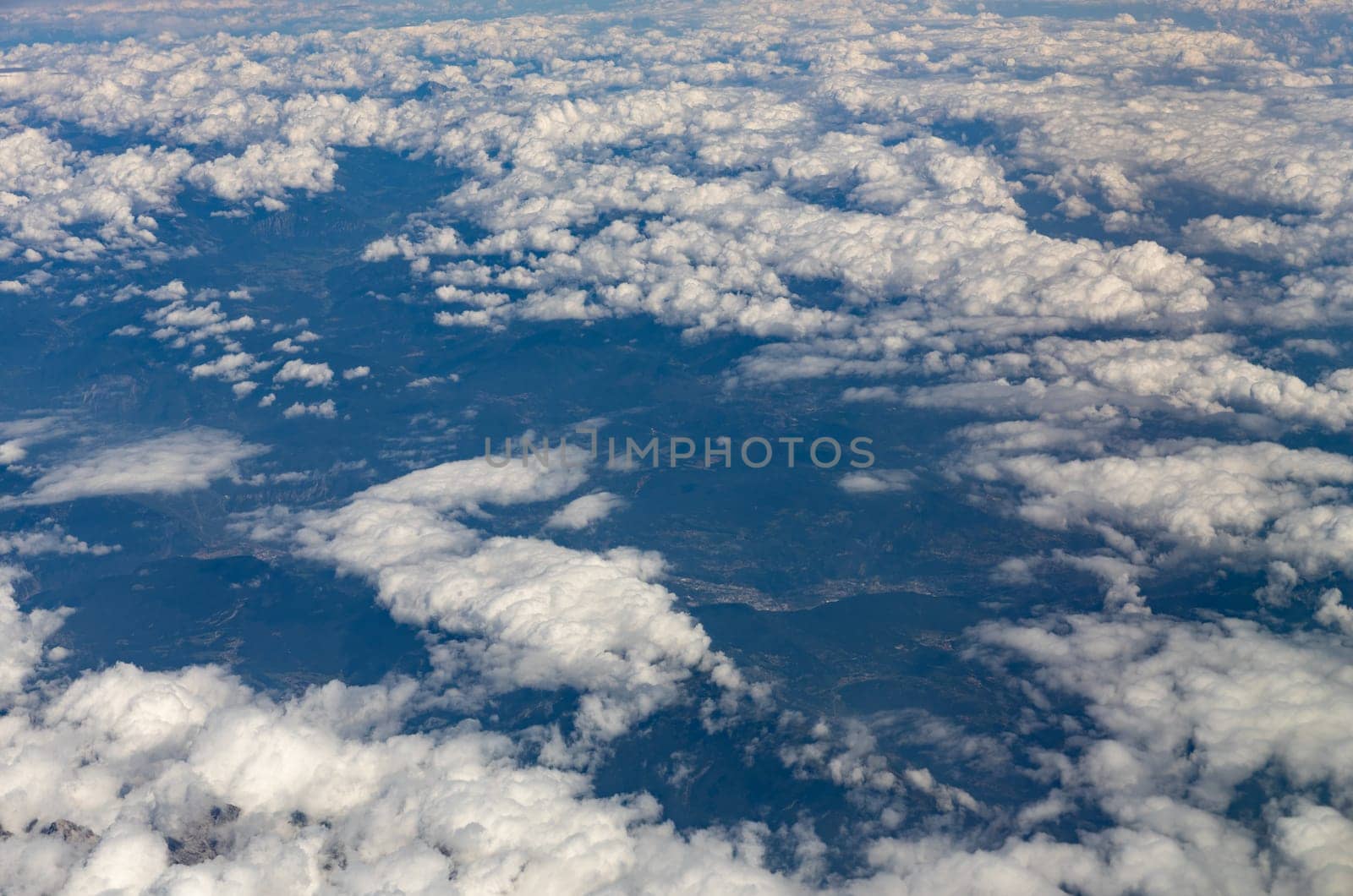 A beautiful view of the white clouds hanging above the ground through the porthole window, side view, close-up.