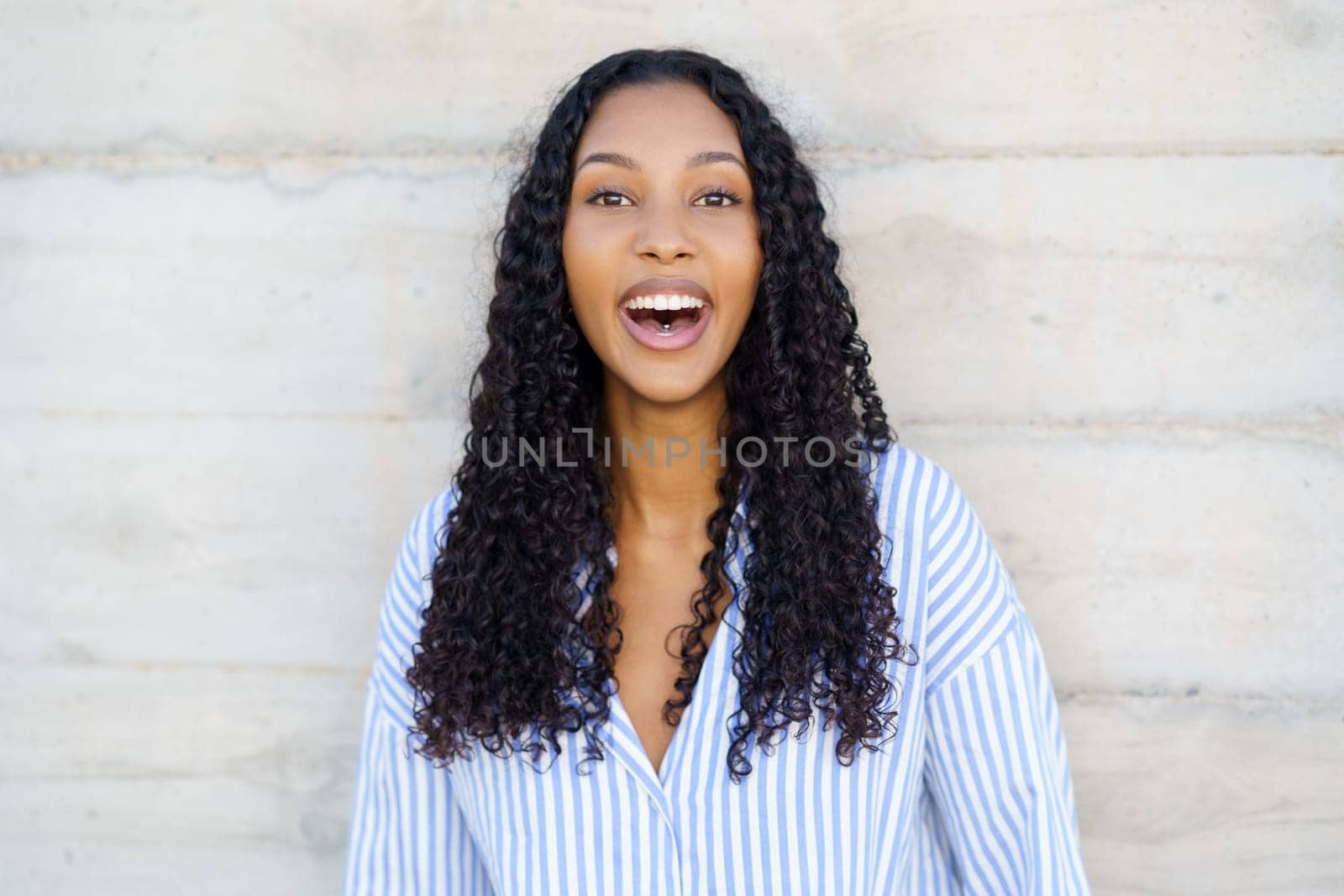 A cheerful young woman with curly hair radiates joy and positivity, leaving a delightful and uplifting atmosphere that is perfectly suited for various lifestyle and wellness themes and topics